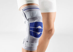 A person standing and wearing a orthoapedic knee brace on their right knee. The brace is a GenuTrain S Model of the brand Bauerfeind which is manufactured in Germany. This brace is great for all types of knee pain especially knee osteoarthritis.