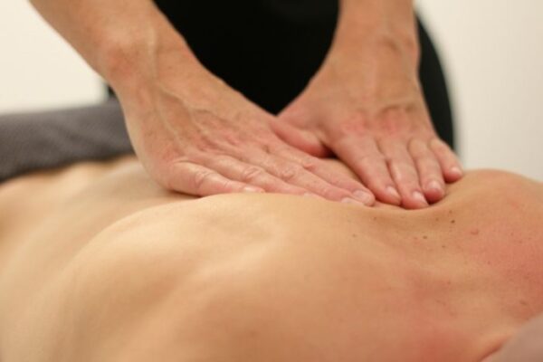 A massage therapist performing a Swedish or relaxation massage to the mid-back of a patient who is laying on their back. Relaxation or Swedish massage is great for stress relief, anxiety relief, and overall good feeling of relaxation.