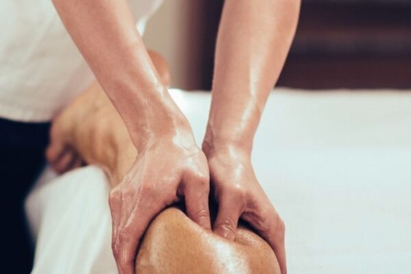 A massage therapist doing deep tissue massge release of the the calves of a patient who is laying on their stomach. Deep tissue massage is a very common form of massage for pain relief and release of stiffness and tightness in the muscles.