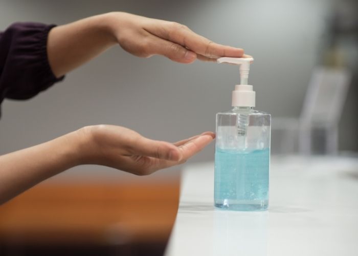 Two young hands reaching for a sanitization bottle