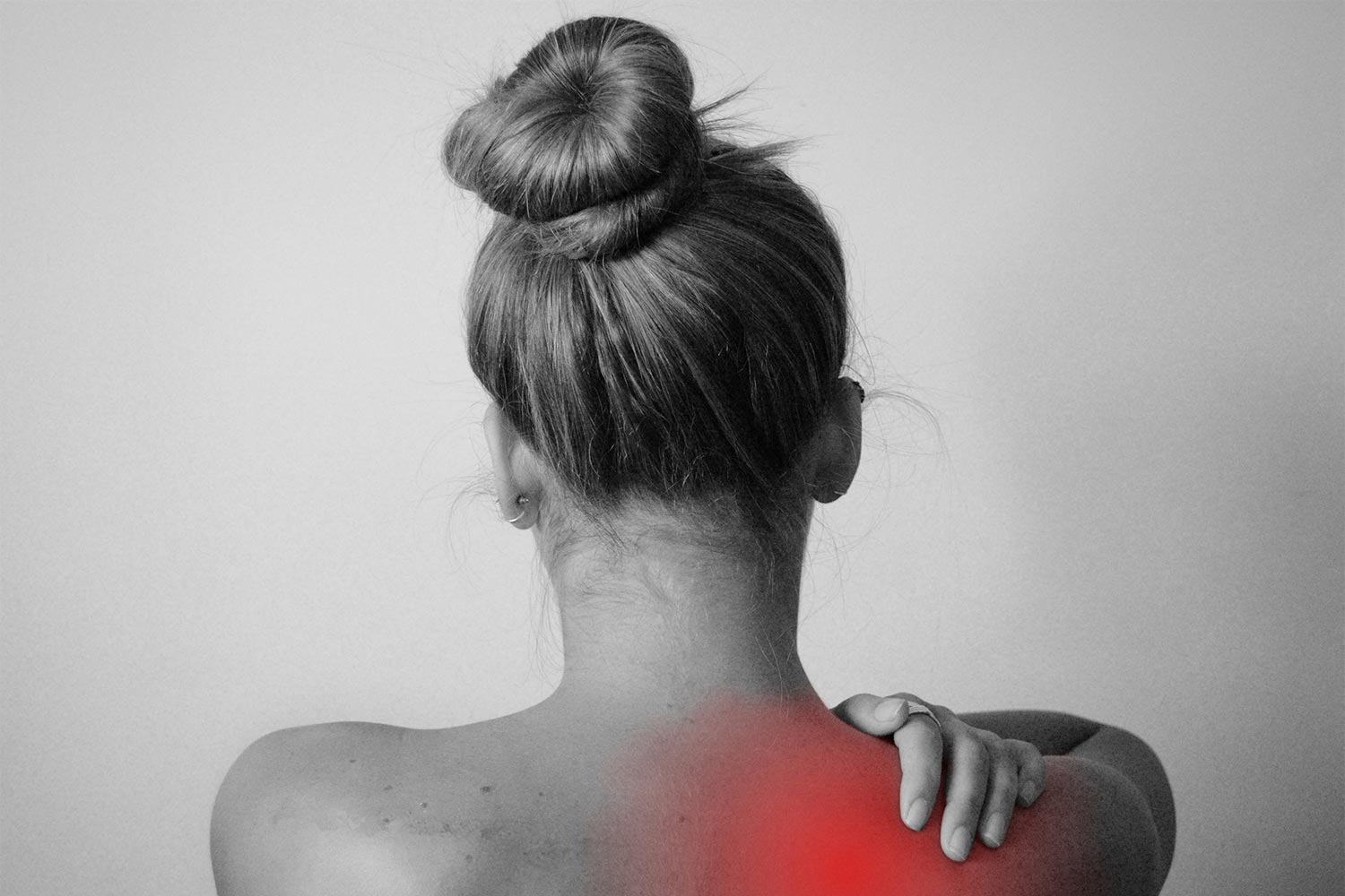 Person holding her shoulder with a red area marking the painful area