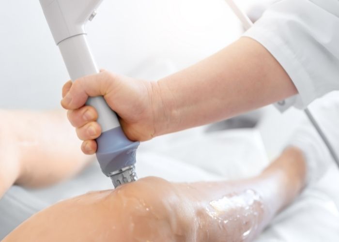 A patient getting shockwave therapy on the inside of their knee. Shockwave therapy is a great treatment technique used by physiotherapists and chiropractors for muscles and tendon pain.