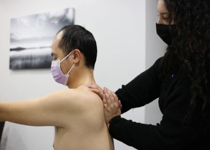 Dr. Marina, a chiropractor performing soft tissue therapy on the mid-back of a patient. She is using an active release technique.