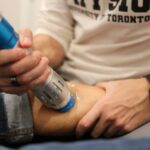 Chris Ibrahim, a physiotherapist at Runway Health in Markham and Newmarket, is providing shockwave therapy to a patient's calf.